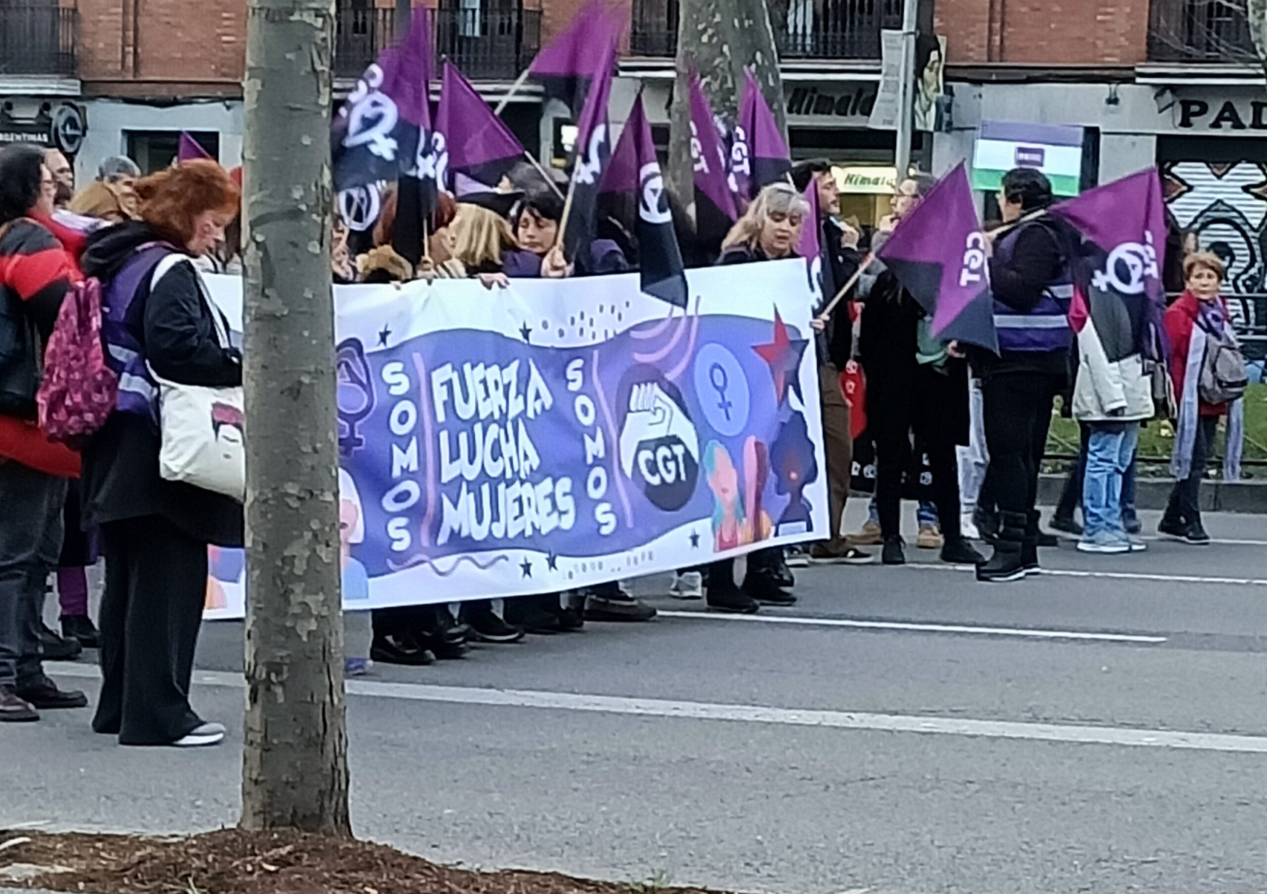 Manifestantes feministas durante el 8 de marzo en Madrid con una pancarta que dice "fuerza, lucha, mujeres".